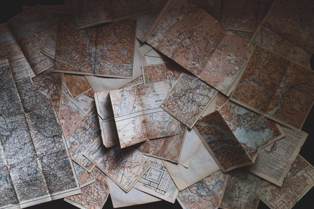 Aerial shot of several old maps spread out over a surface