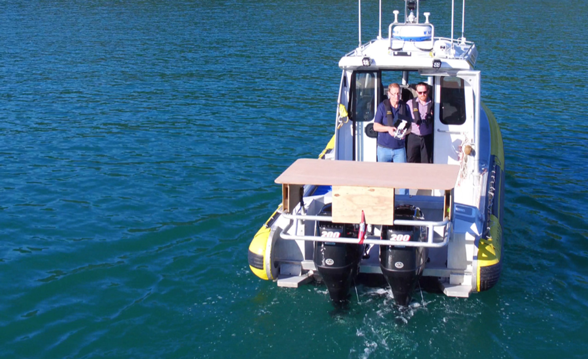 A boat on the water, two men standing in the doorway of the cokpit