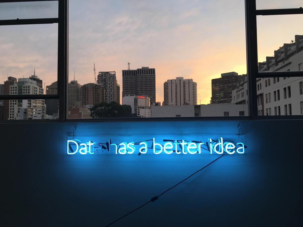 Twilight skyline with blue neon sign “data has a better idea”