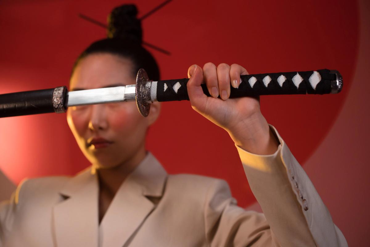 Woman in beige suit holding a samurai sword