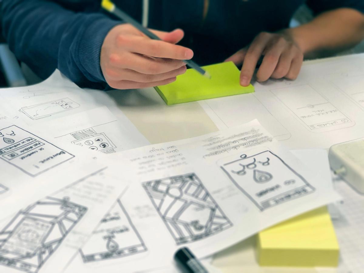 Person sketching wireframes on post-it notes at a desk