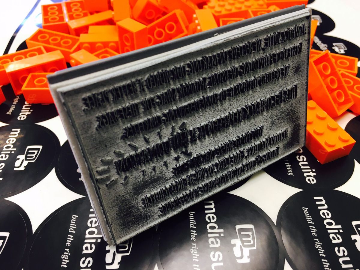 A sheet of Media Suite stickers covered with orange lego bricks and a stamp on its side