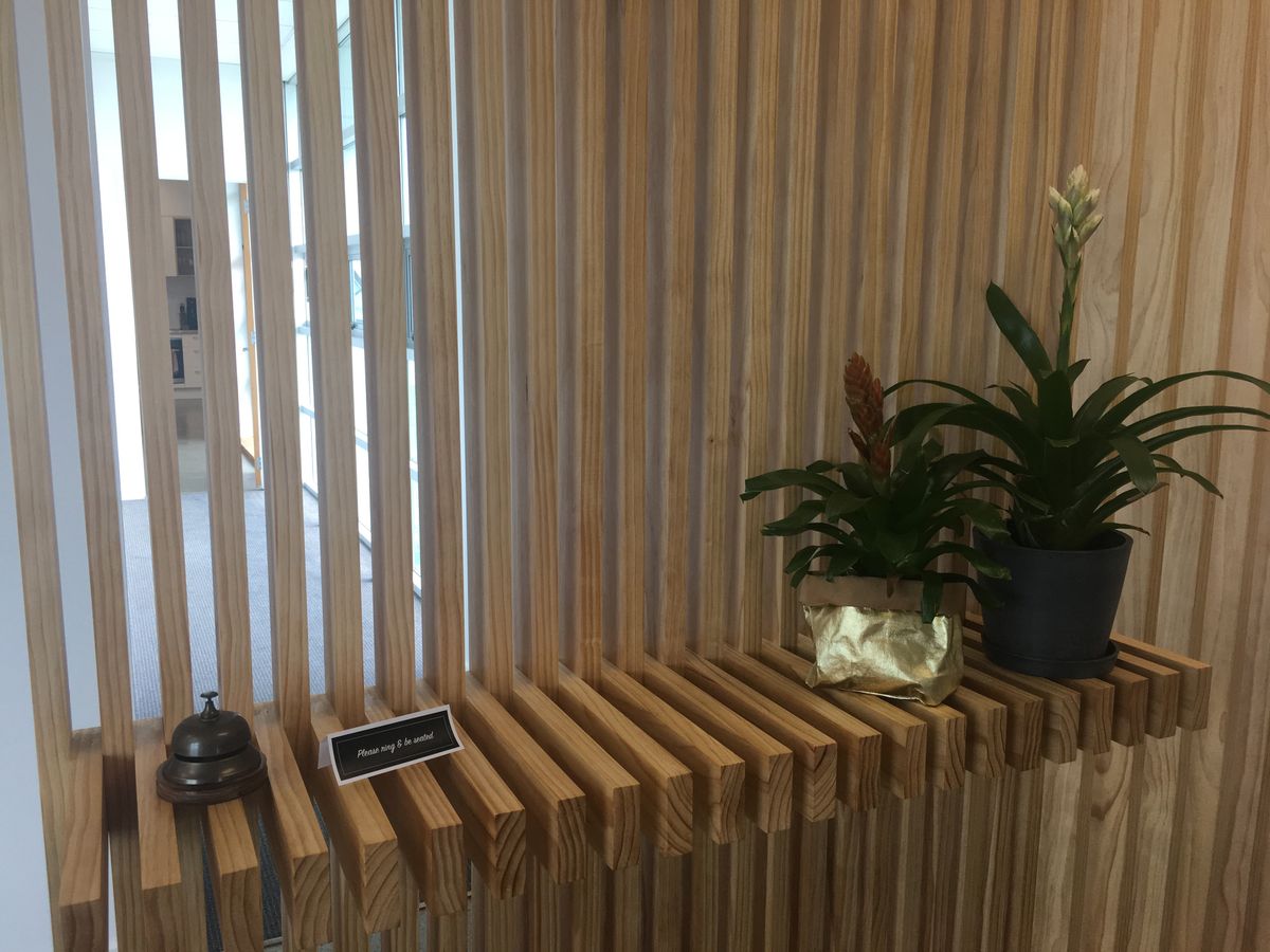 Timber screening and shelf holding a reception bell and two pot plants.