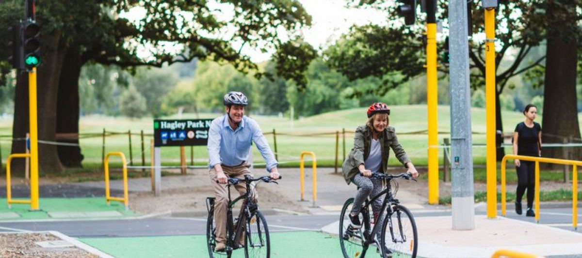 2 older adults on bikes crossing the road at Hagley Park in Christchurch