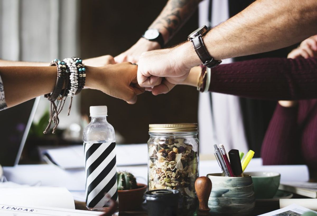 five people fist-bumping over a table