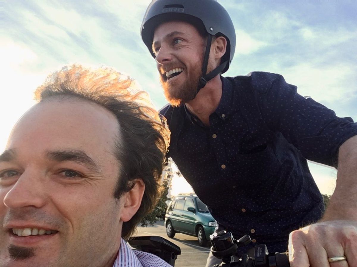 A person wearing a helmet riding a bike and another person's face in front of him