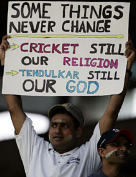 Man holding a sign above his head which says "Some things never change: Cricket still our religion; Tendulkar still our God"