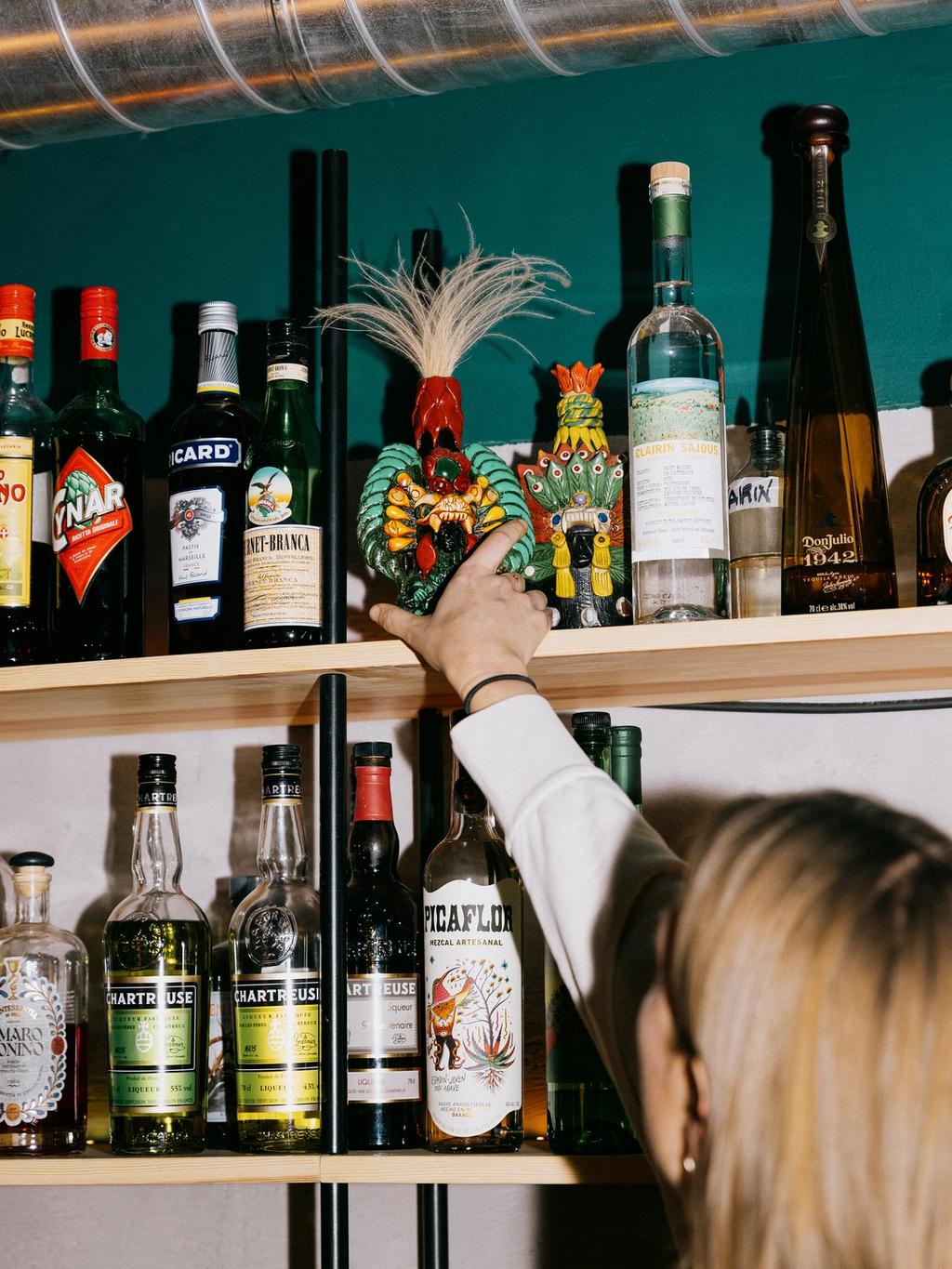 Hylla bak baren er eklektisk pyntet – blant annet med obskure meksikanske spritflasker.