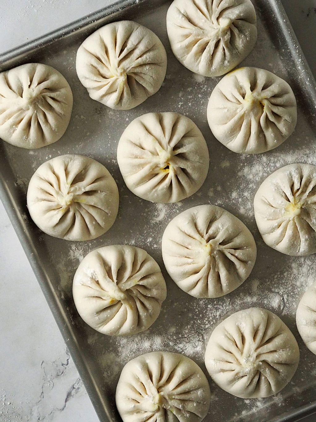 Baozi-buns brettes med begge hender, i en rotasjonsbevegelse. Det er lurt å se videoen på Instagram!