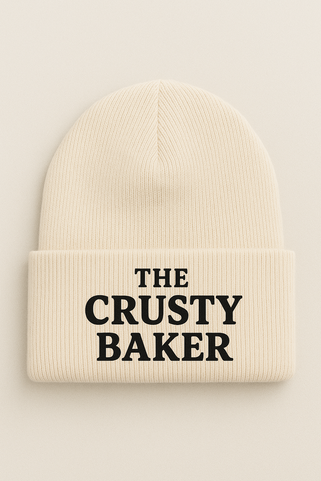 A cozy knit beanie with “The Crusty Baker” embroidered in bold lettering, perfect for keeping warm in style.