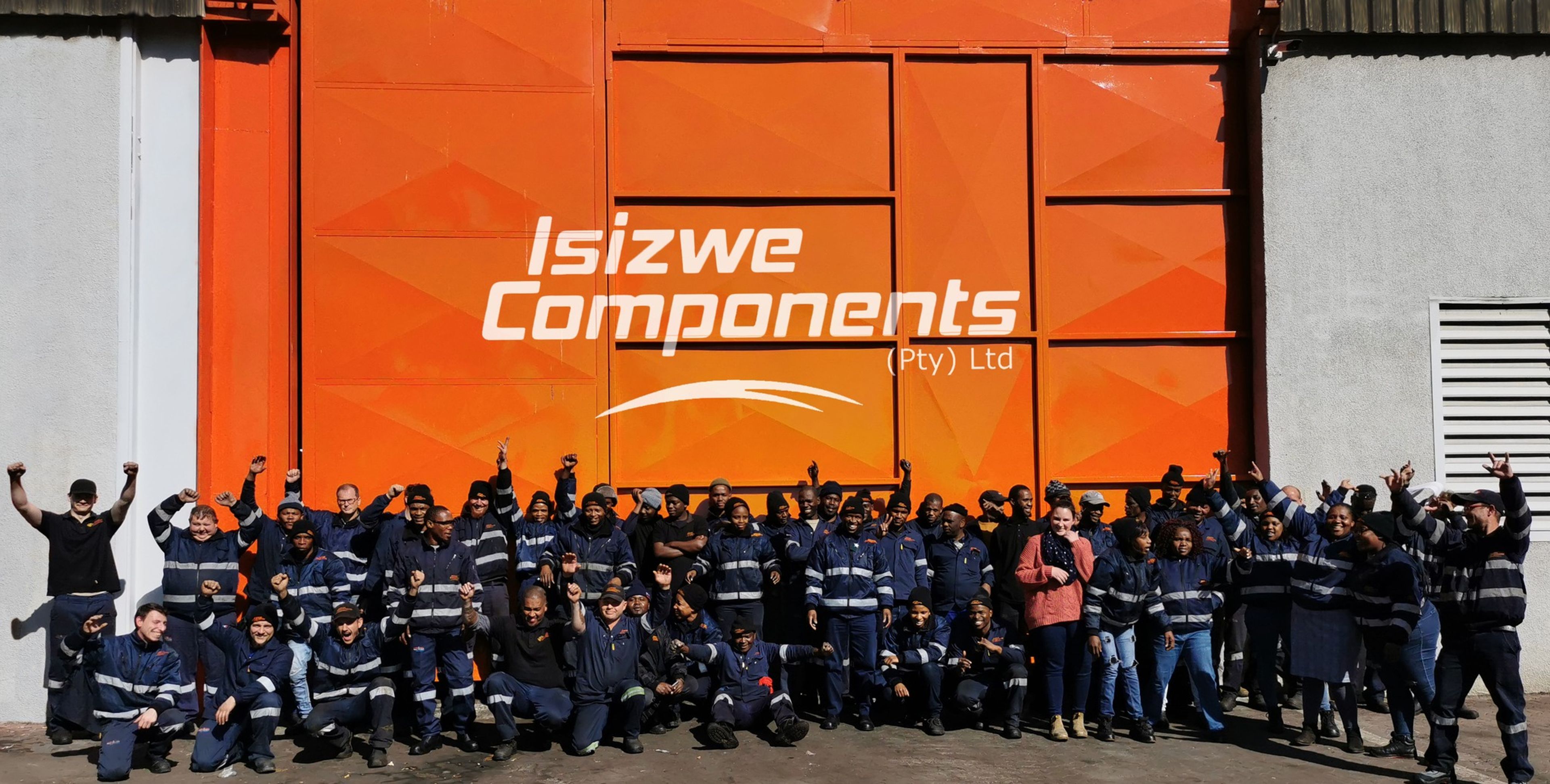 a large group of people are posing for a picture in front of an orange building .