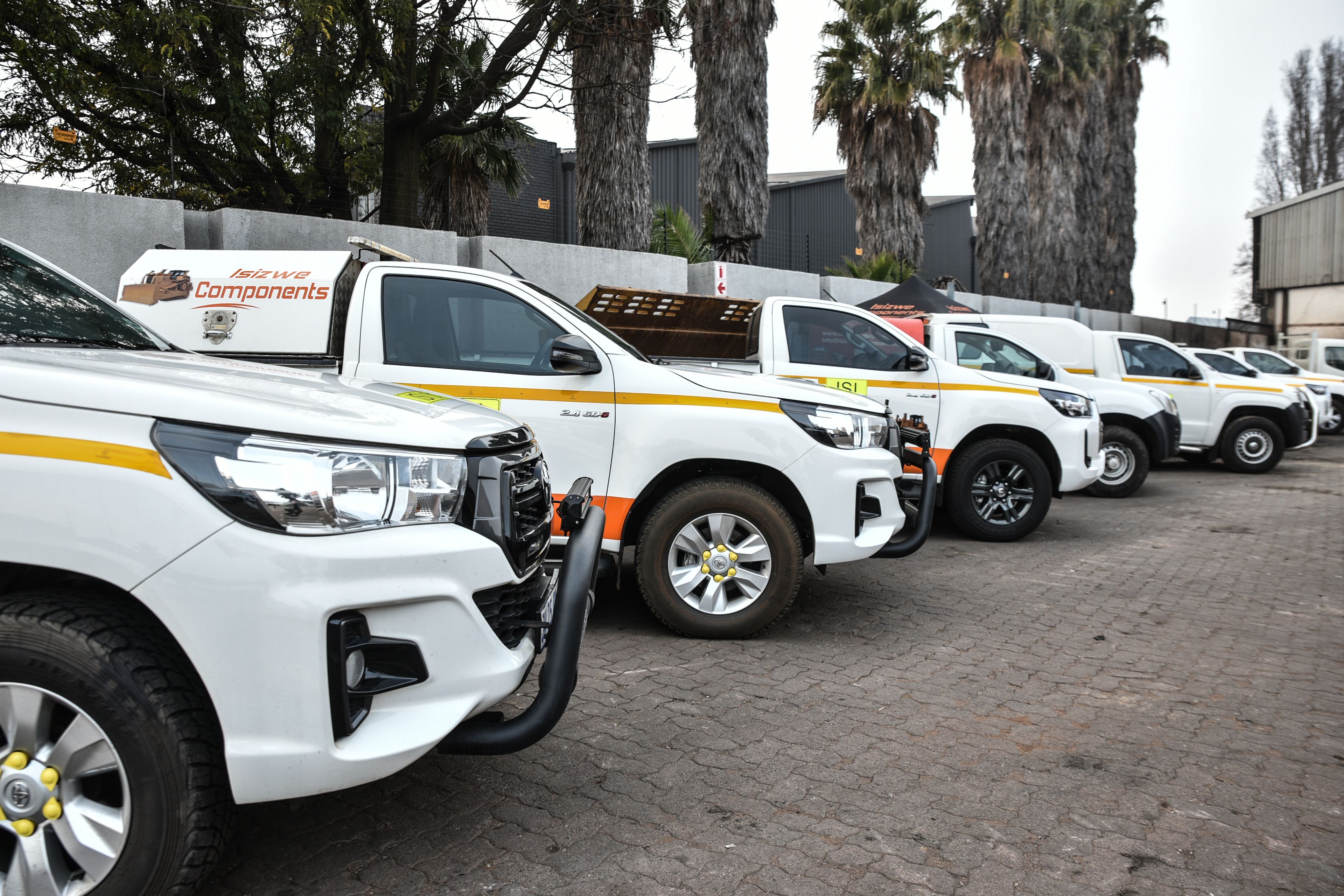 a row of white trucks parked next to each other in a parking lot .