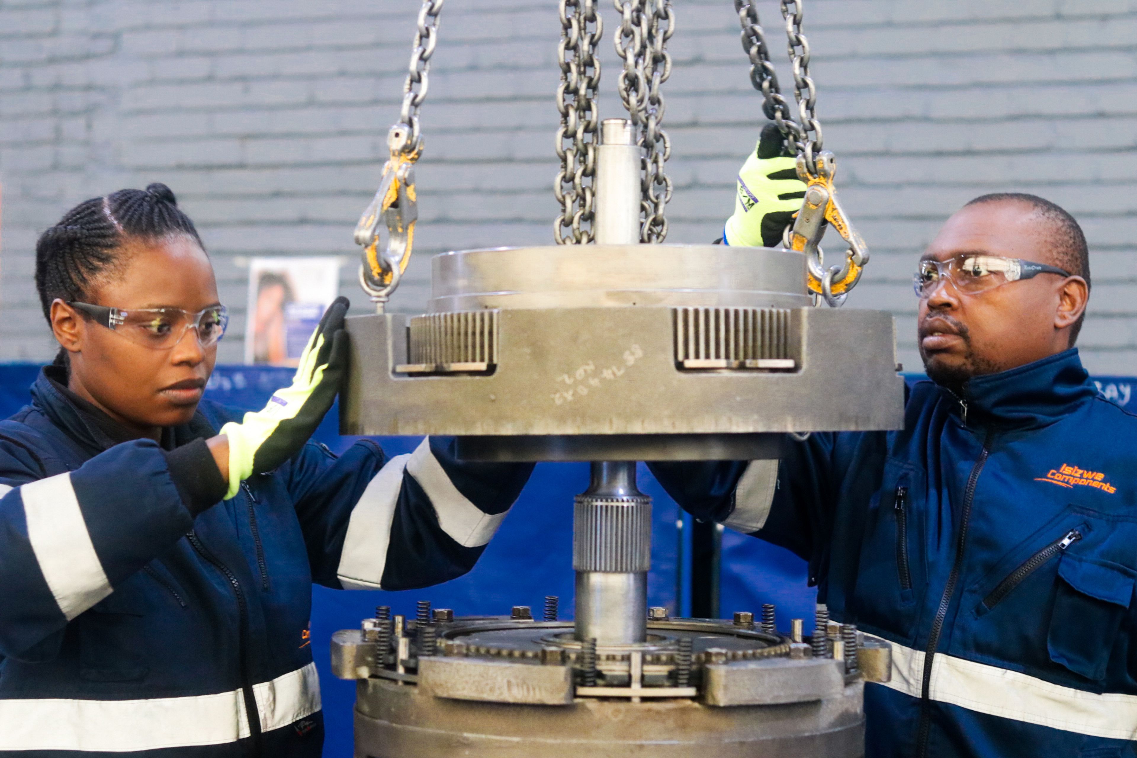 a man and a woman are working on a machine in a factory .