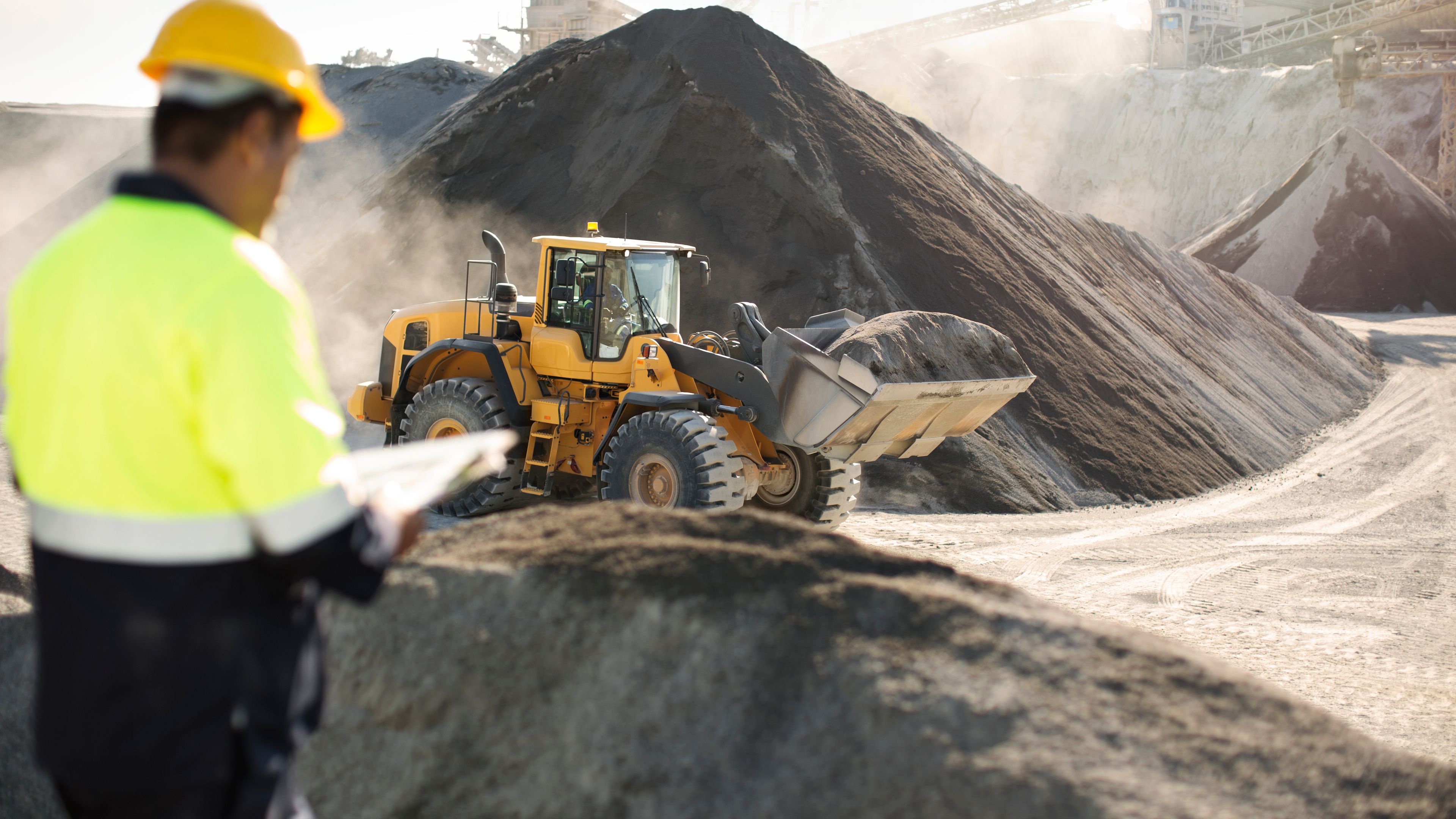 a man is standing in front of a pile of dirt and a bulldozer .