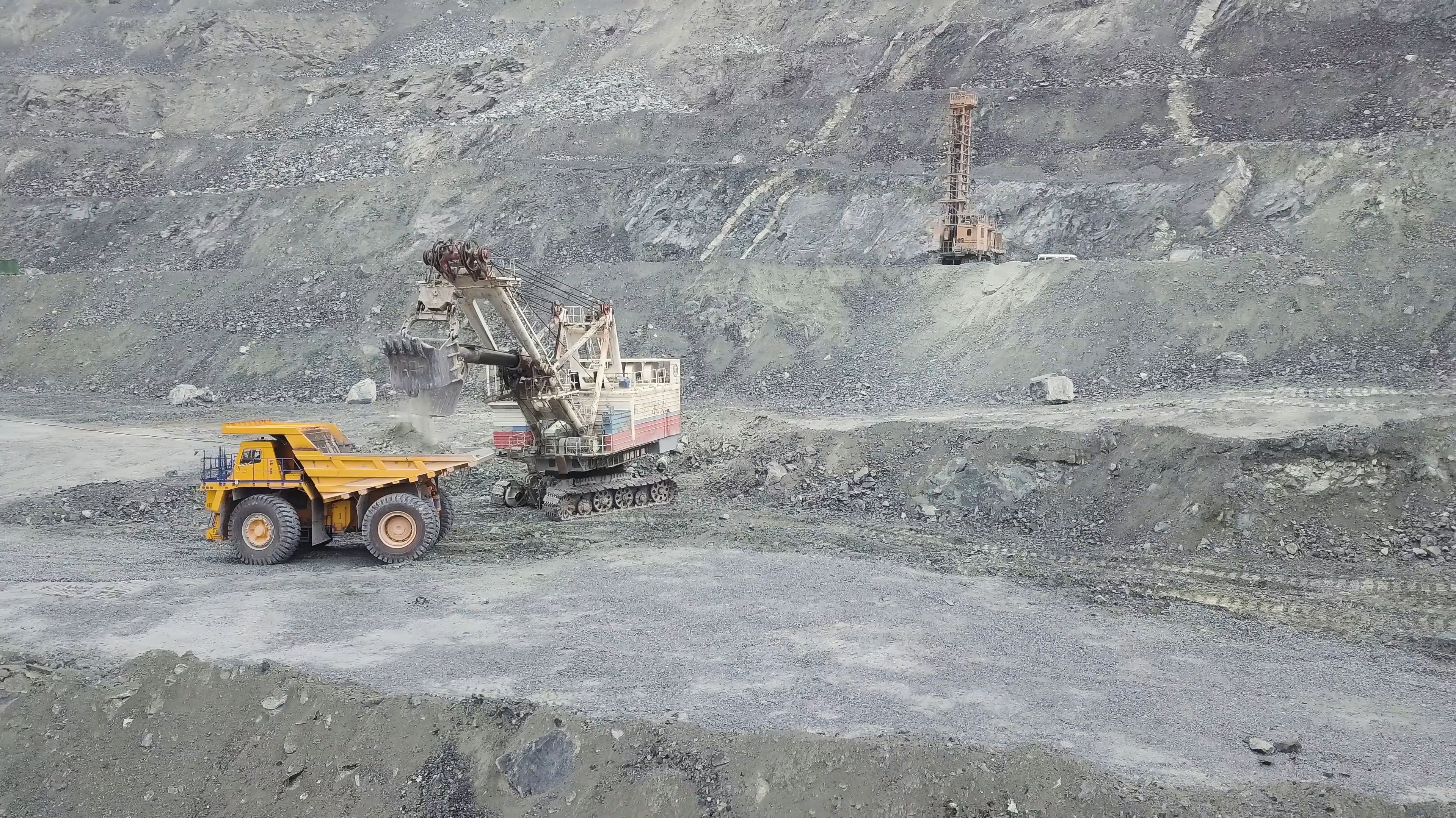 a yellow dump truck is driving down a dirt road in a coal mine .