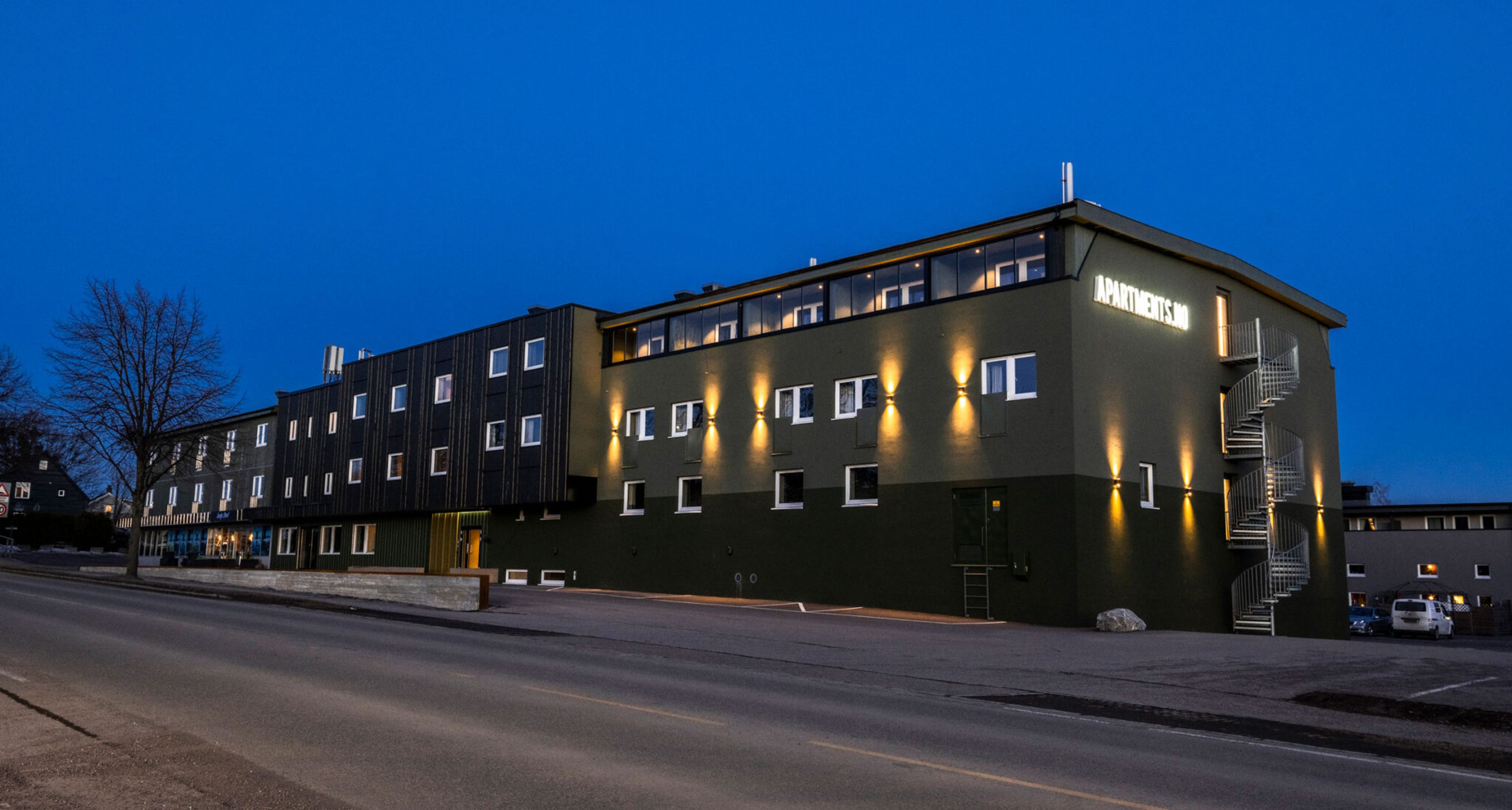Mottaket i Horten i skumringen – en langstrakt bygning med opplyst fasade og «Apartments»-skilt.