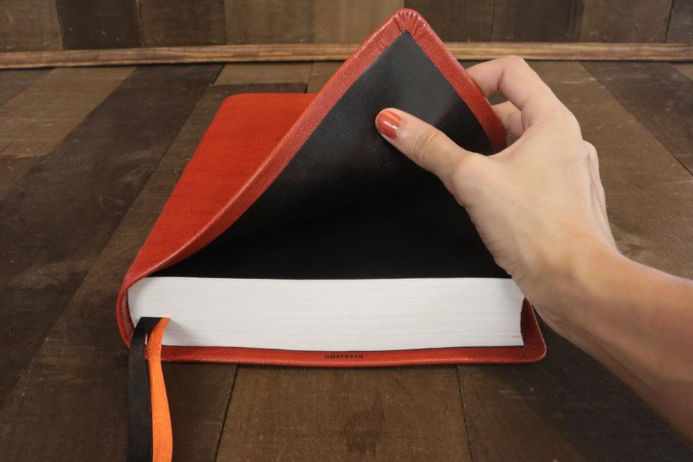 Hand holding open a red goatskin leather Bible to show its flexible cover