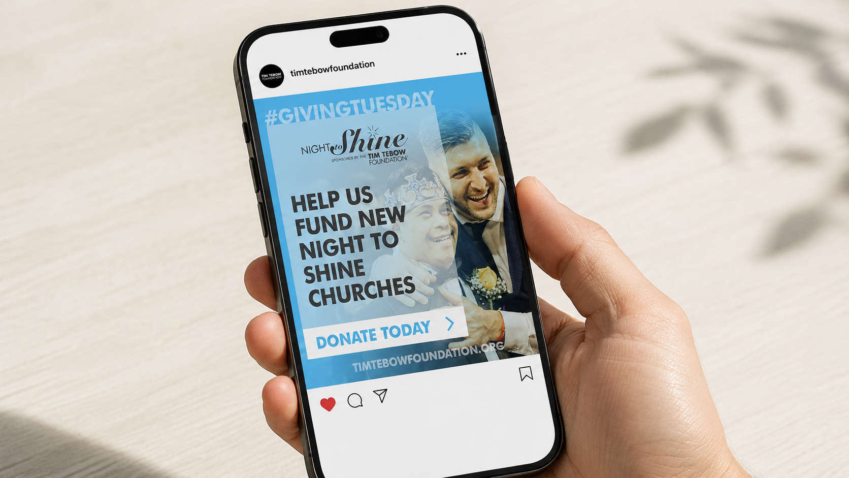 Instagram post mockup on a phone showing a Tim Tebow Foundation #GivingTuesday “Night to Shine” graphic, held in hand