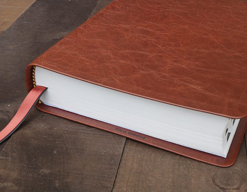 Brown Italia cowhide leather Bible resting on a rustic wood table