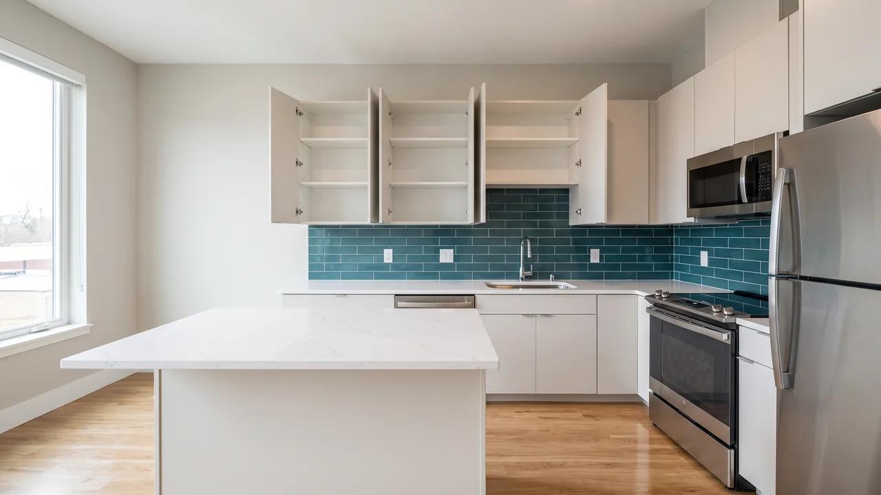 A clean, empty apartment kitchen with bare counters and open cabinets, ready for a new resident