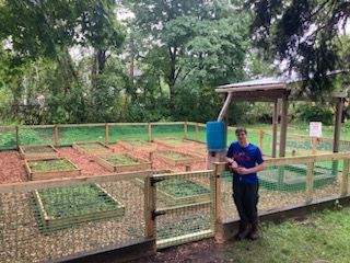 An eagle Scout poses with our garden, which he helped improve as his Eagle Scout project