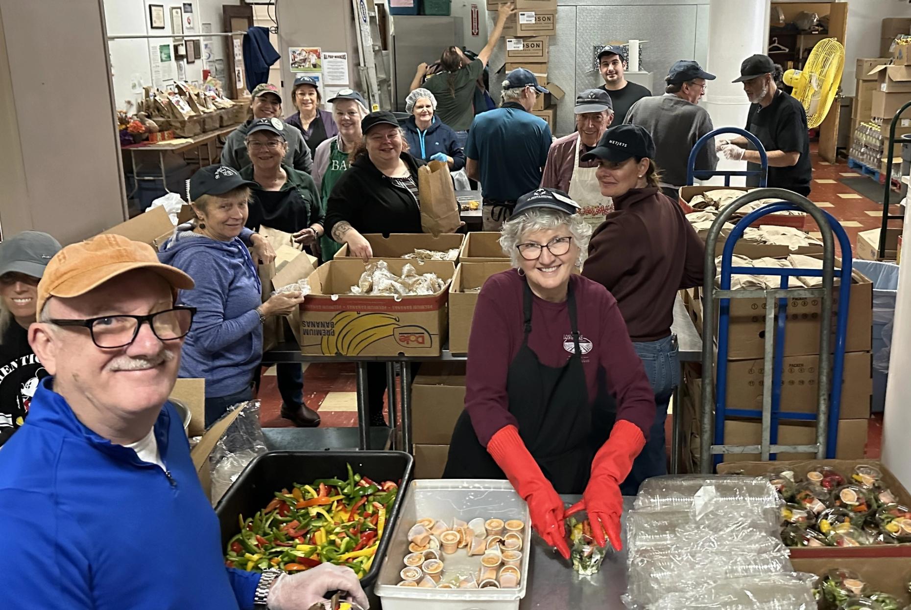 Many smiling and busy volunteers prepping for Thanksgiving dinner