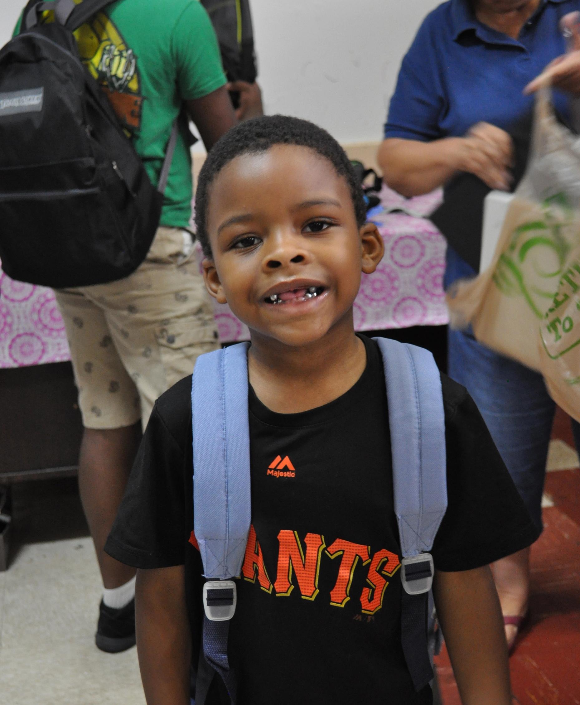 Young child wearing his new backpack and smiling.