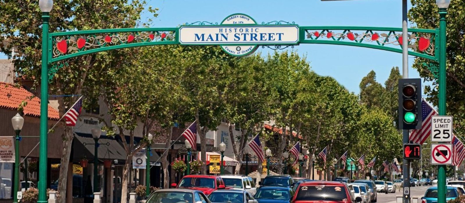 Historic Main Street arch in Garden Grove with American flags and tree-lined Garden Grove Boulevard
