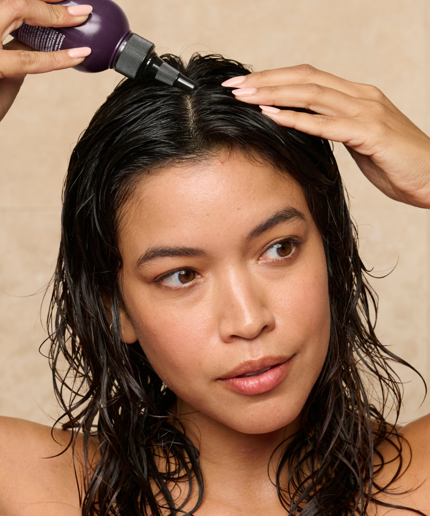A model with wet hair applies some Dr. Groot Miracle In Shower Treatment to her scalp.