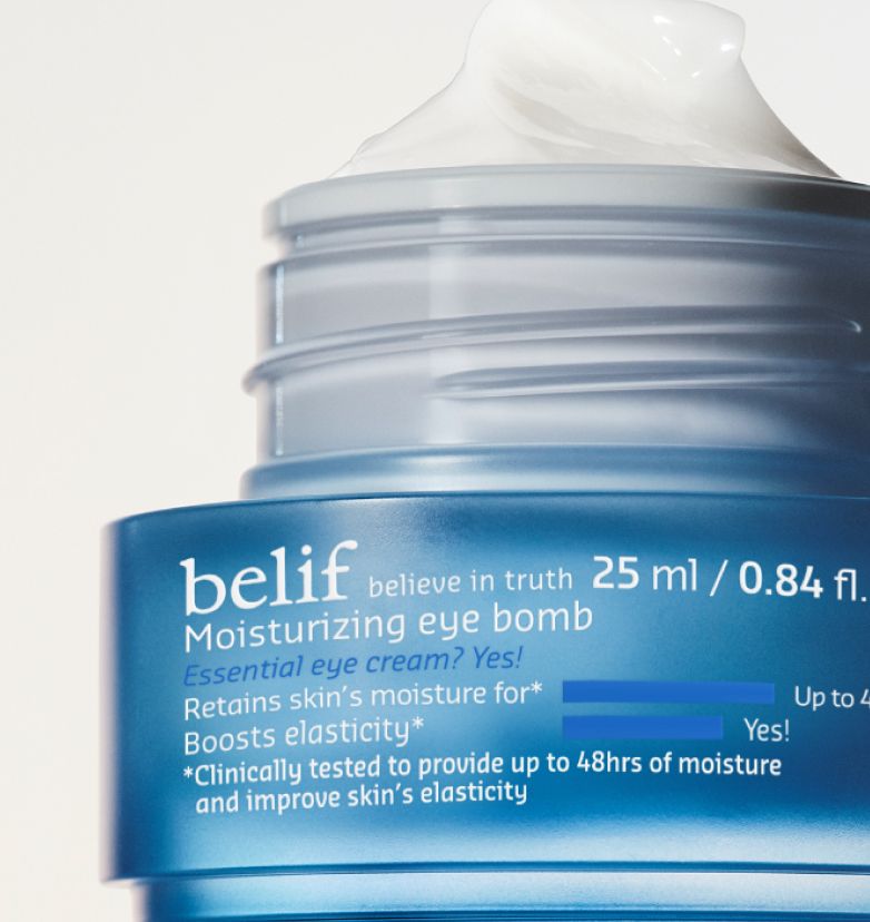 A closeup of a blue jar of belif Moisturizing Eye Bomb with the lid removed and creamy whipped texture exposed on a white background.