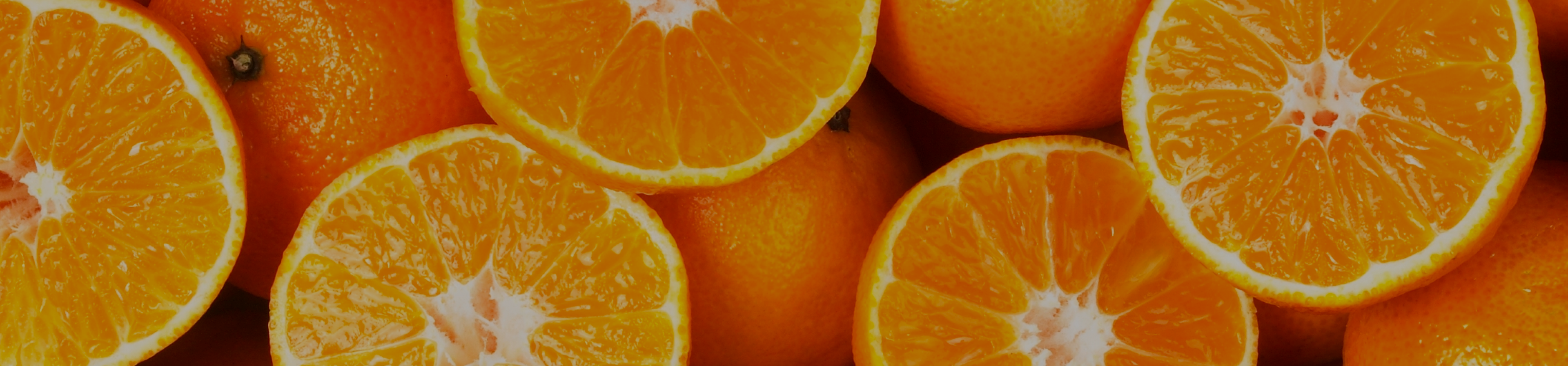 A wide horizontal image of a bunch of orange fruits - some whole, some cut in half