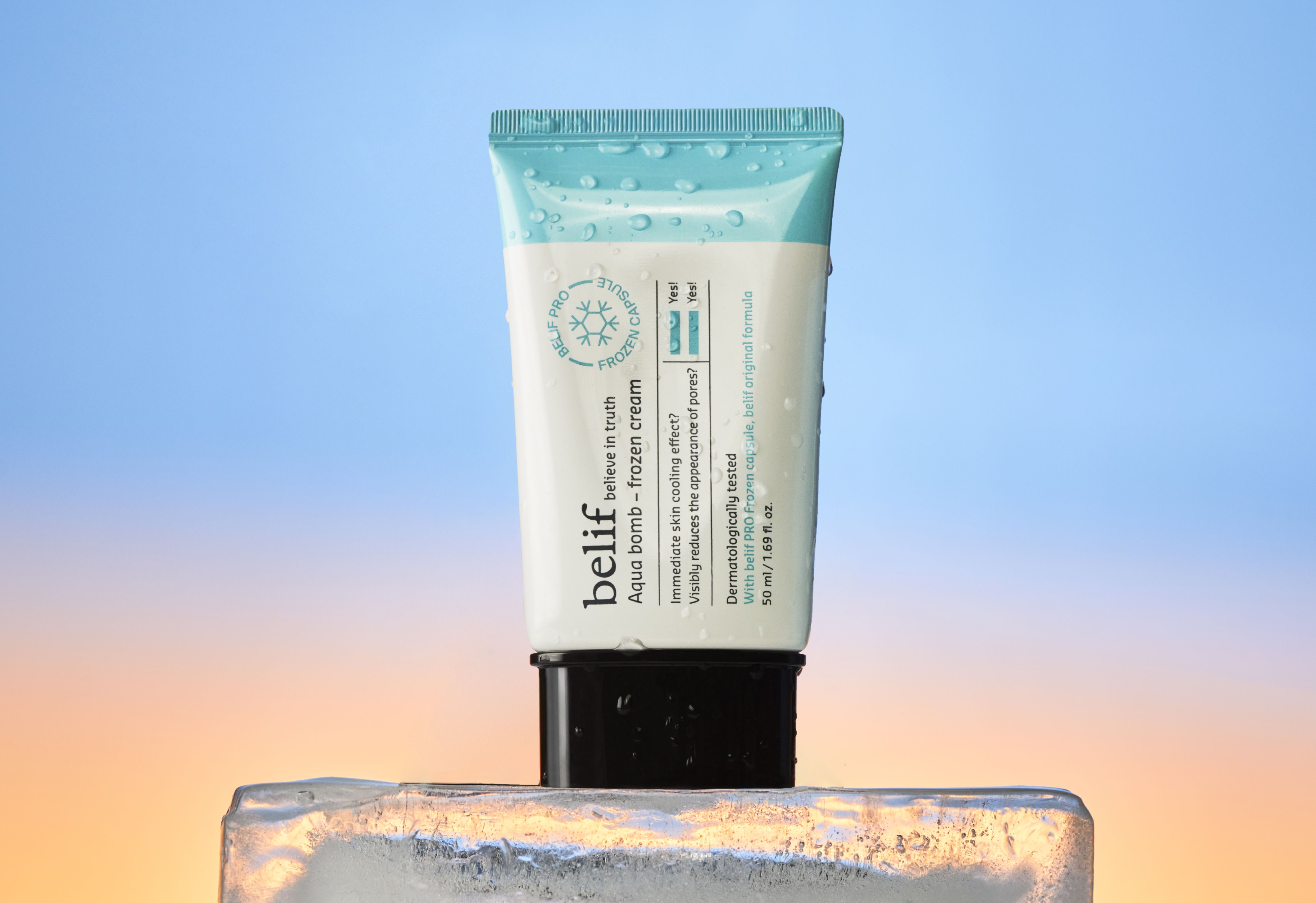 A tube of Belif Aqua Bomb frozen cream, covered in water droplets, stands on a block of ice.