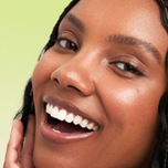 Smiling Black woman with braided hair and radiant skin.