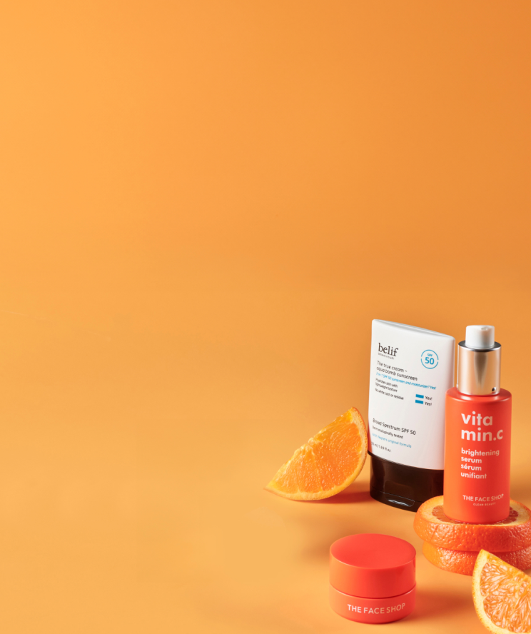 belif Aqua Bomb Vitamin C Cream, The Face Shop Vitamin C Lip Mask and Serum with slices of oranges and an orange background.