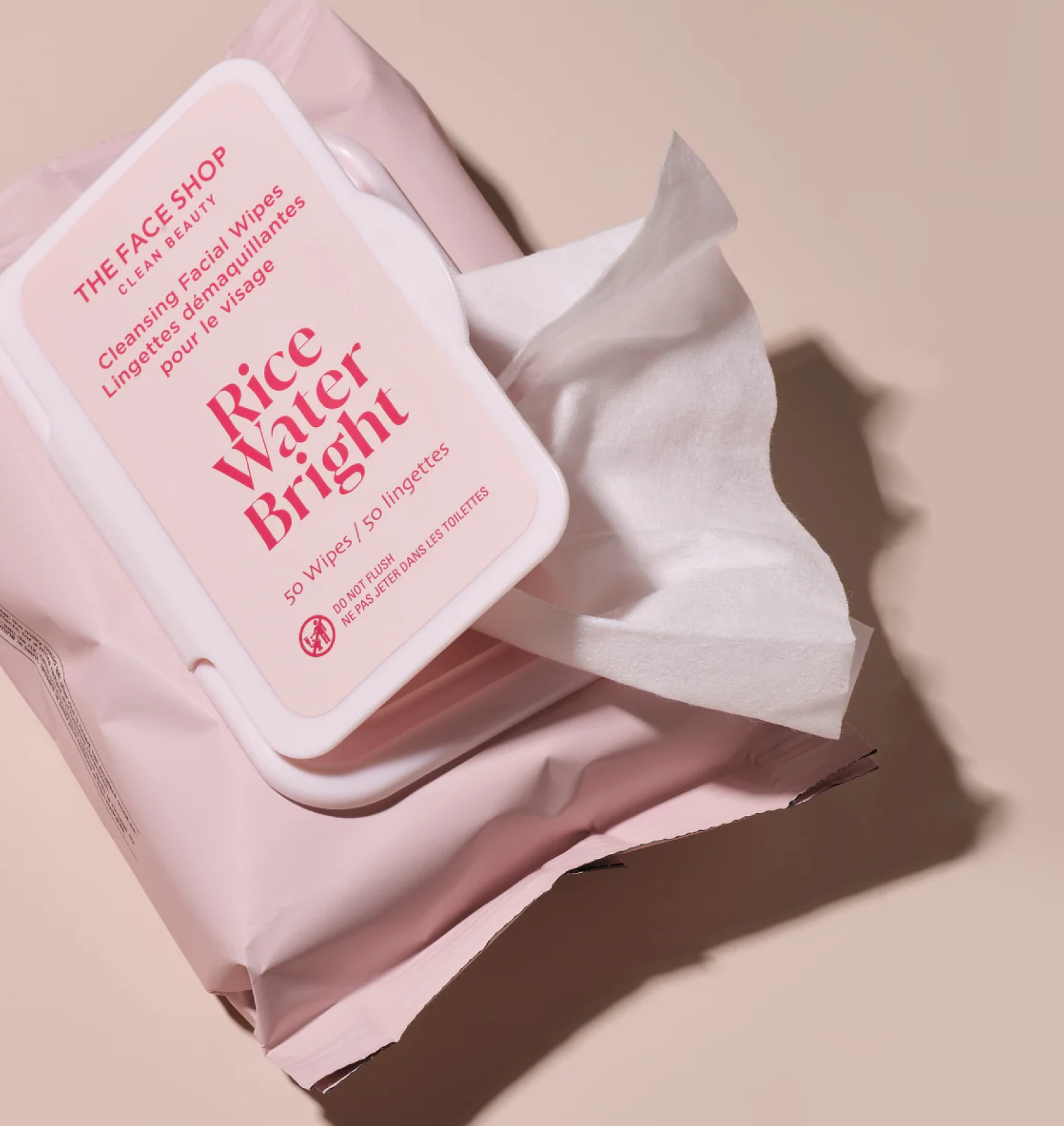 An open pack of The Face Shop Rice Water Bright Cleansing Facial Wipes with one tissue wipe slightly pulled out on a warm beige background.