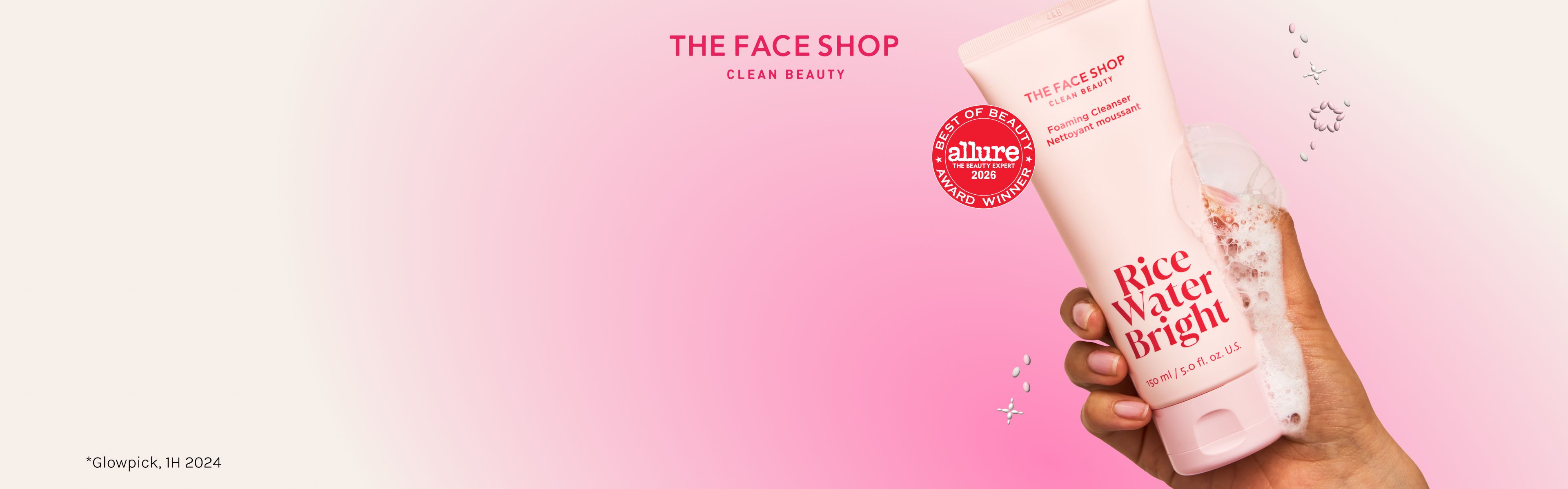 The Face Shop Rice Water Bright Foaming Cleanser in a pink tube, held by a hand with foam, displays an Allure Best of Beauty 2020 award on a pink gradient background.