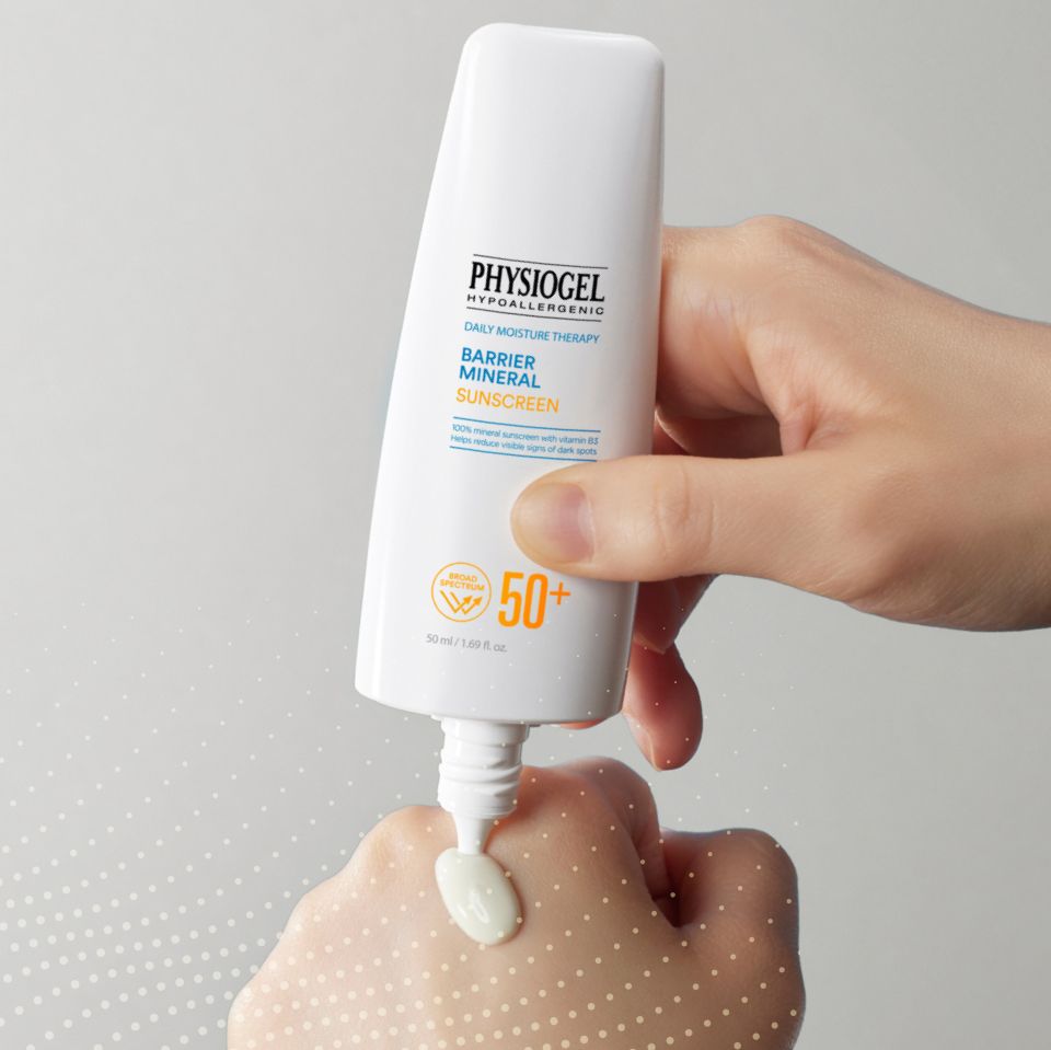 A hand is squeezing a tube of Daily Moisture Therapy Barrier Mineral Sunscreen SPF 50  onto an hand.