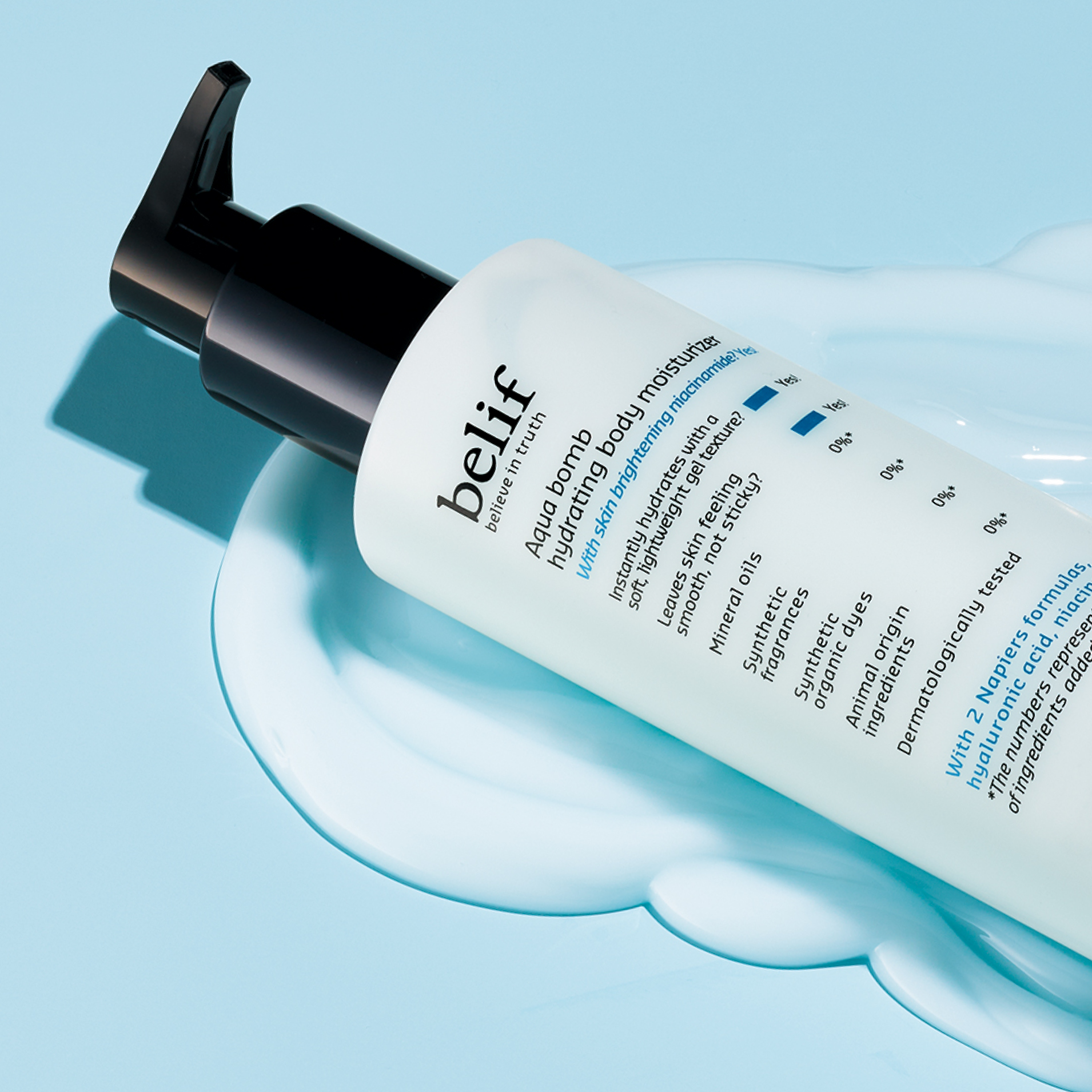 A white bottle of belif Aqua Bomb Hydrating Body Moisturizer lying in a puddle of the moisturizer on a light blue surface