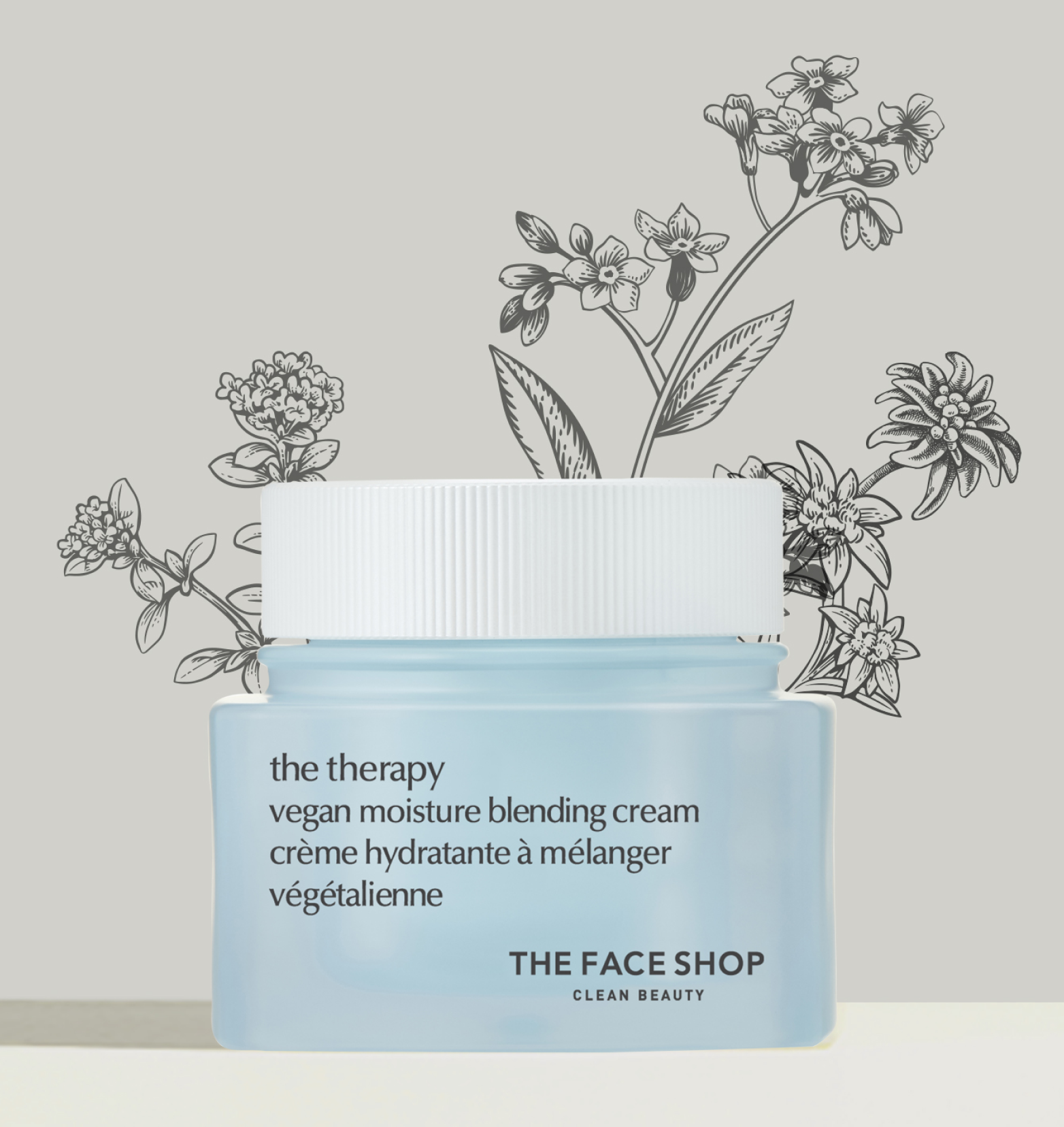 A light blue jar of The Face Shop Vegan Moisture Blending Cream standing on a beige background with a  drawing of flowers