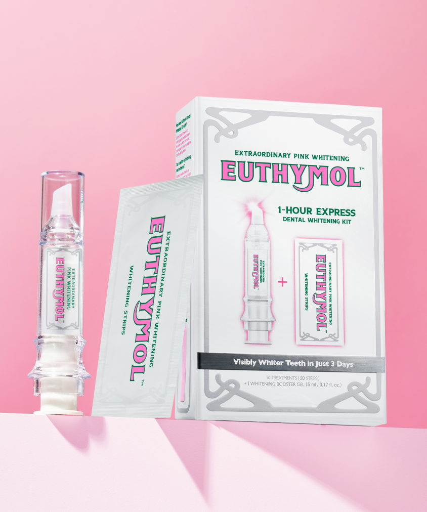 A Euthymol 1-hour Express Dental Whitening Kit box standing on a pink surface along with its content: a white tube of Euthymol Whitening Gel and one of the whitening stips.