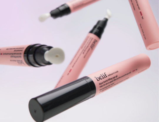 Multiple pink belif Aqua bomb lifting eye gel tubes with black caps, some open to white pump applicators, are shown floating.