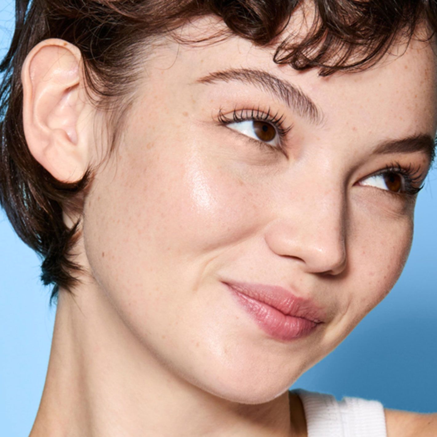 A model is happy showing smooth skin on blue background for belif skincare.