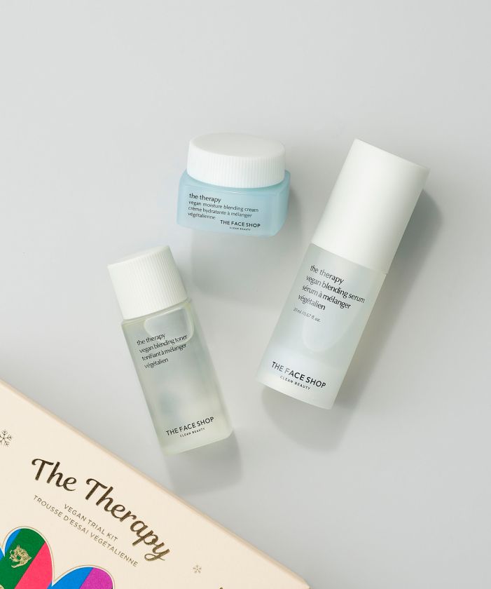 Three skincare products from The Face Shop The Therapy Trial Kit, including a cream, serum, and cleanser, are neatly arranged on a light background, next to their outer packaging.
