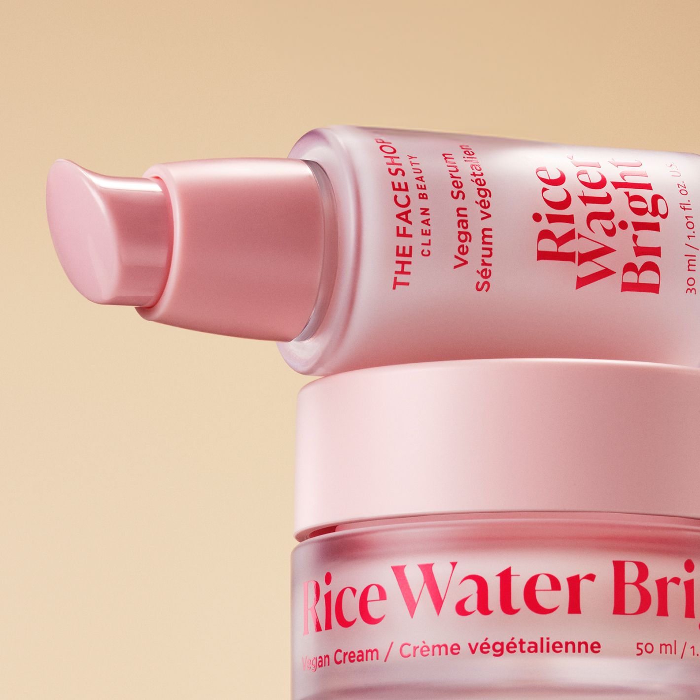 Close-up of a jar of The Face Shop Rice Water Bright Vegan Cream with Rice Water Bright Vegan Serum laid horizontally on top with a warm beige background.