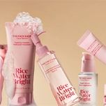A closeup of Rice Water Bright collection, with the Foaming Cleanser in center covered in foam\on a warm beige background.