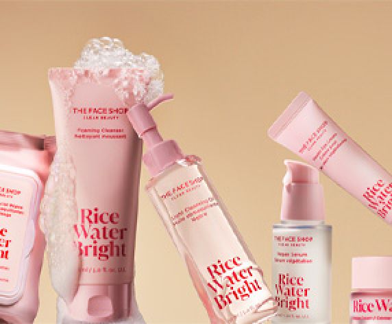 A closeup of Rice Water Bright collection, with the Foaming Cleanser in center covered in foam\on a warm beige background.