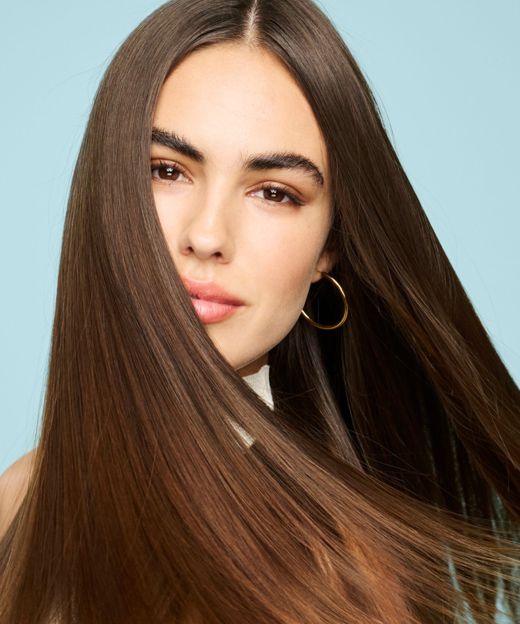 A model with healthy and shiny hair looks at the camera while her hair waves around.