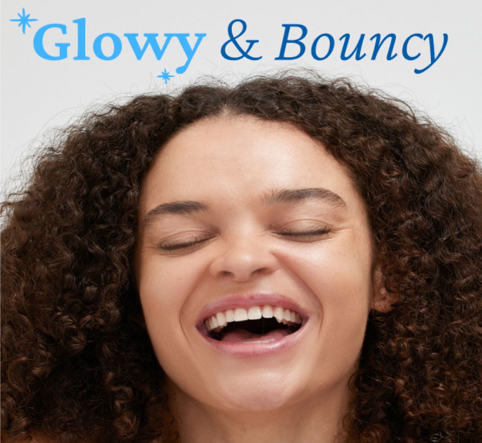 A person with curly hair is laughing joyfully with closed eyes and an open mouth. The background is plain and light-colored, emphasizing the person's happy expression. A text above reads '''Glowy & Bouncy"