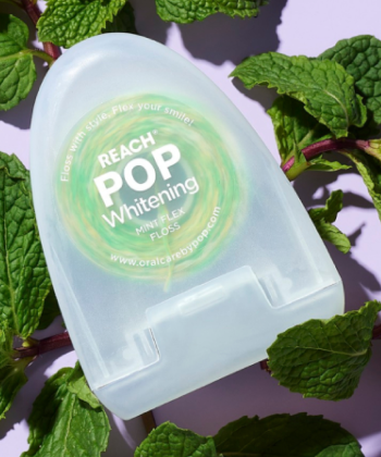 Reach POP Whitening Mint Flex floss laying on top of mint leaves and a light purple surface.