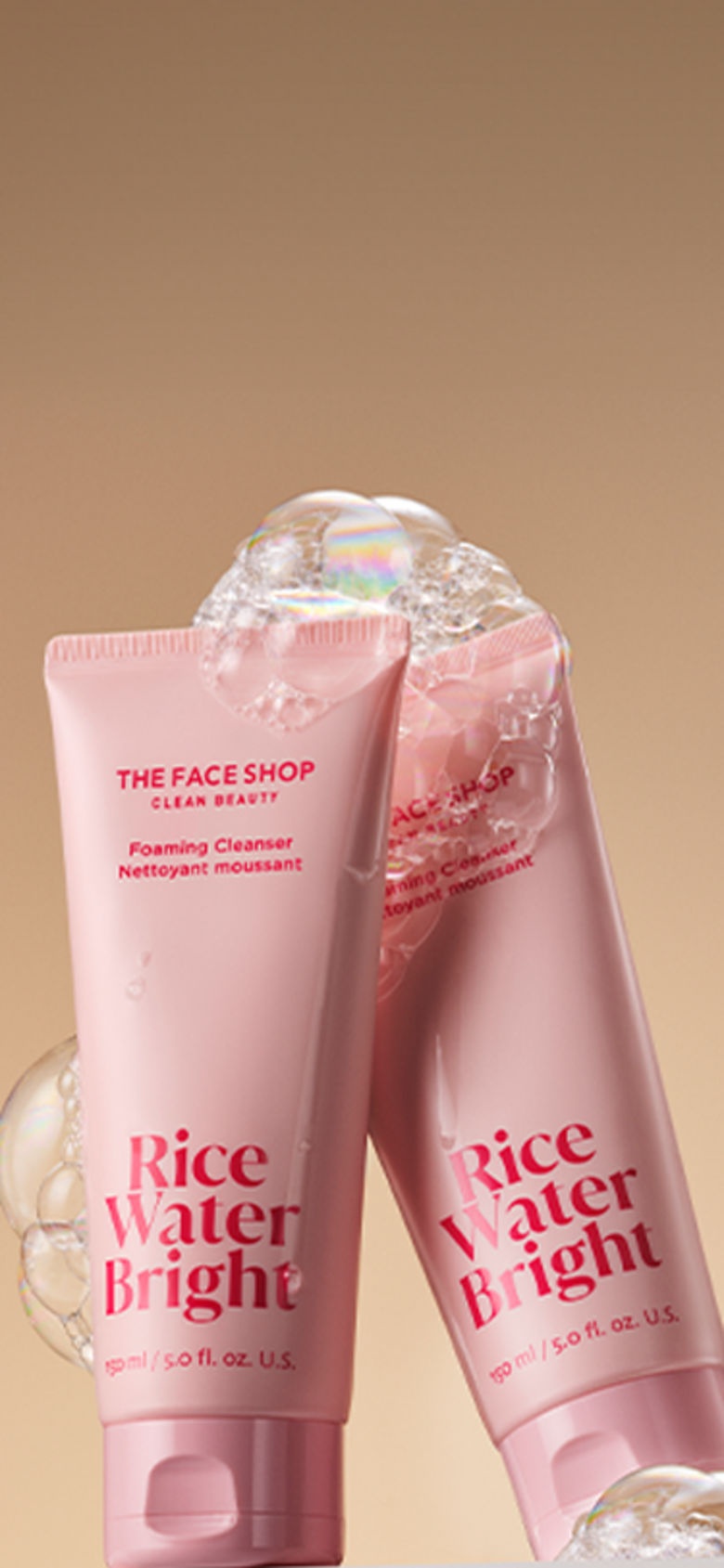 Two tubes of the face shop rice water bright cleansing foam covered in bubbles are displayed on a warm beige background.
